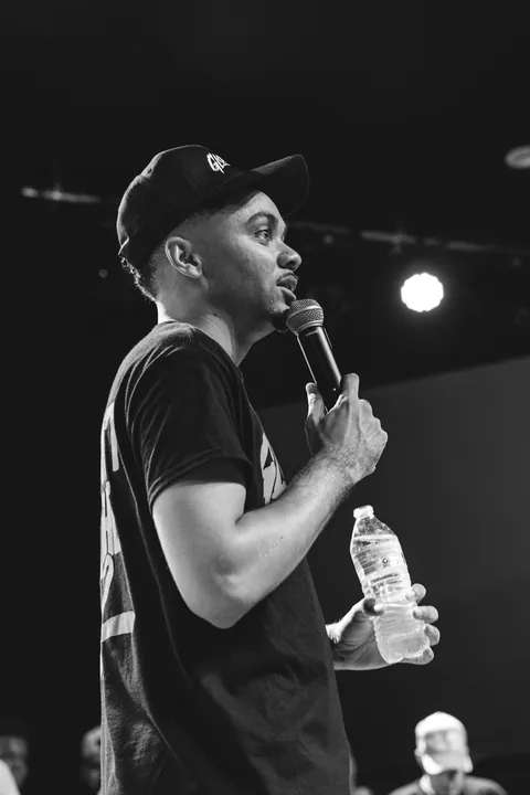 Black and white photo of a performer in a cap speaking into a microphone